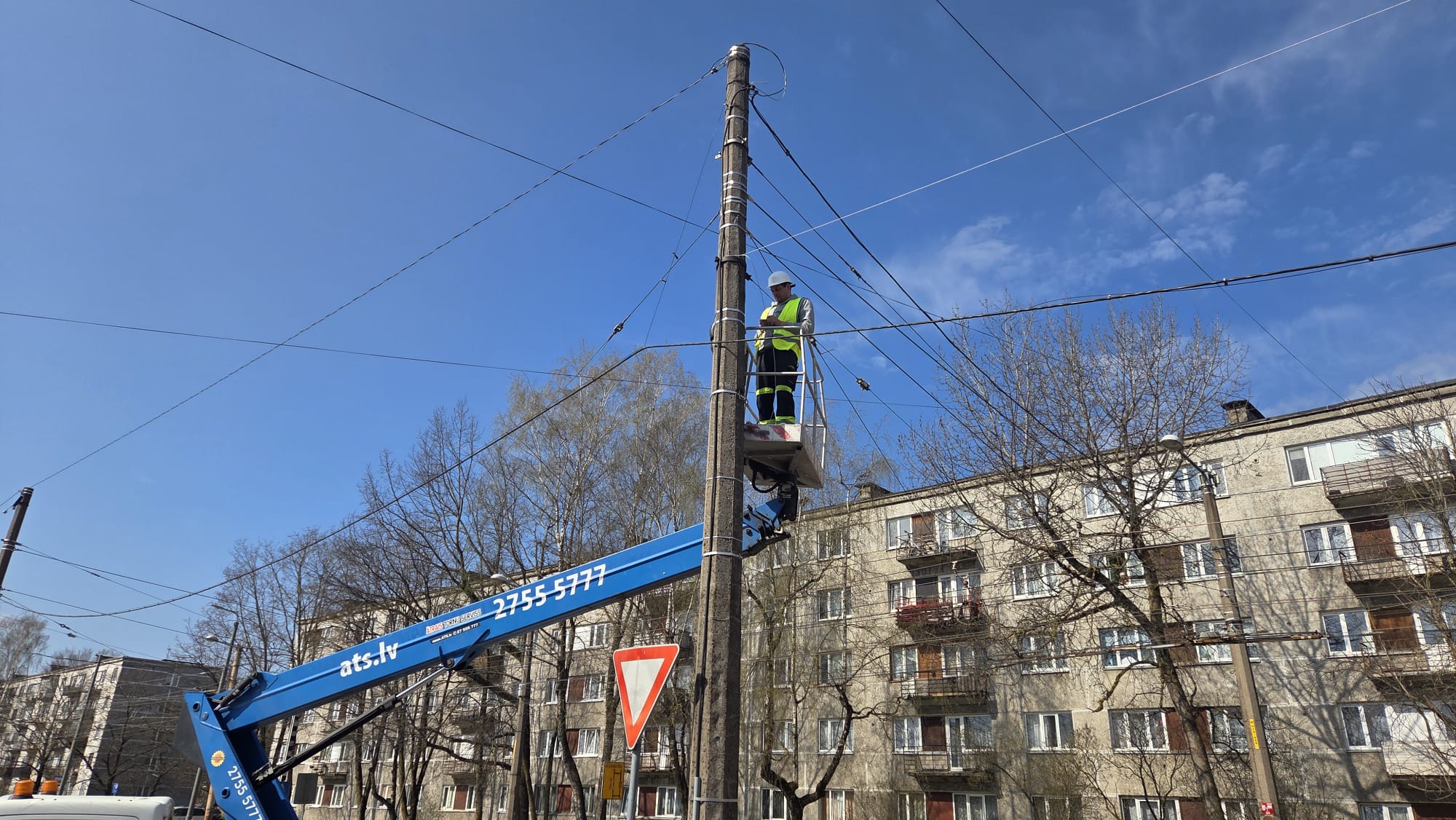 Elektriķis augstuma pacēlājā strādā pie augstsprieguma kabeļu līnijas
