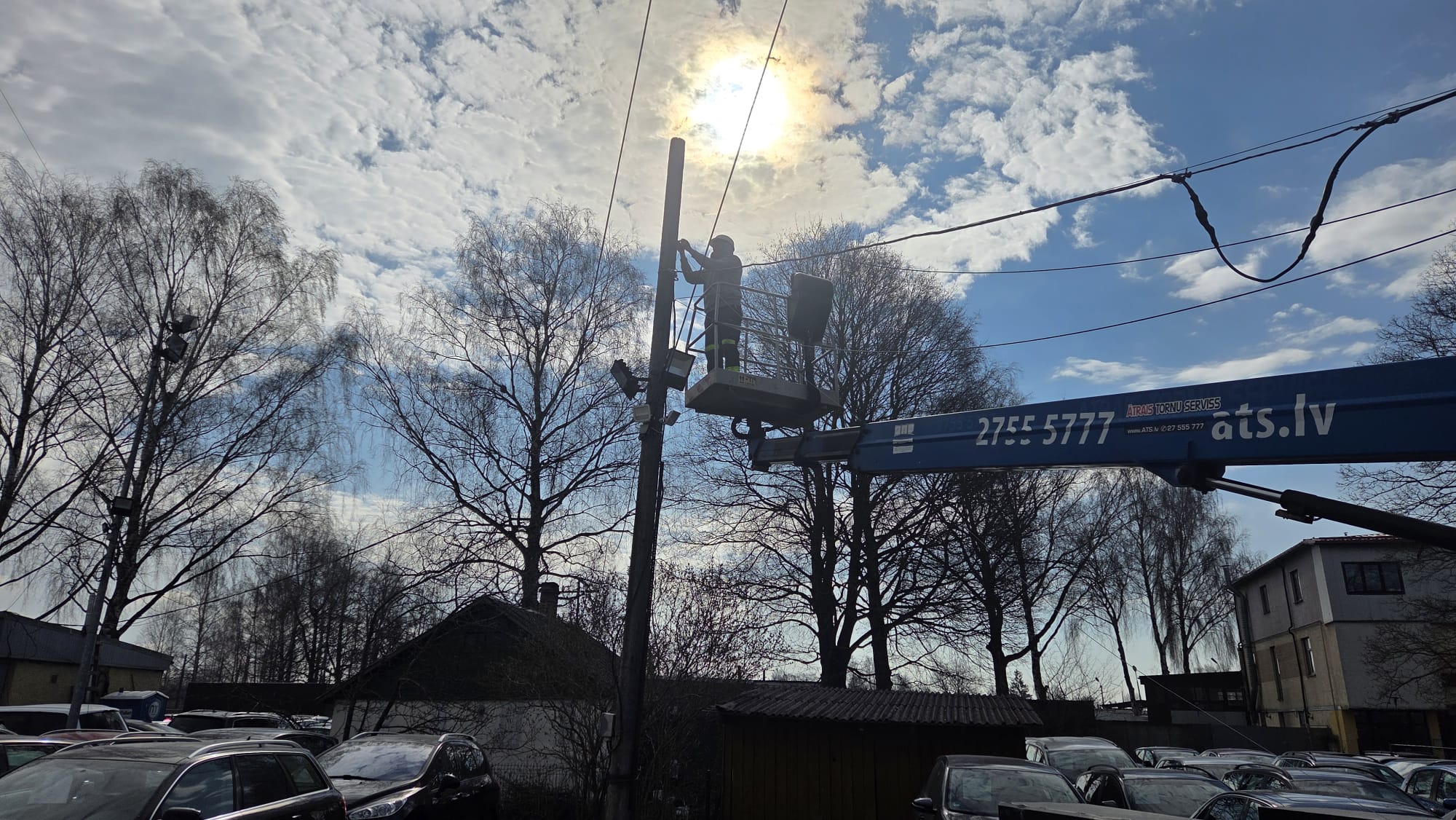 Elektriķa siluets pacēlājā uz saulrieta fona, augstuma darbi